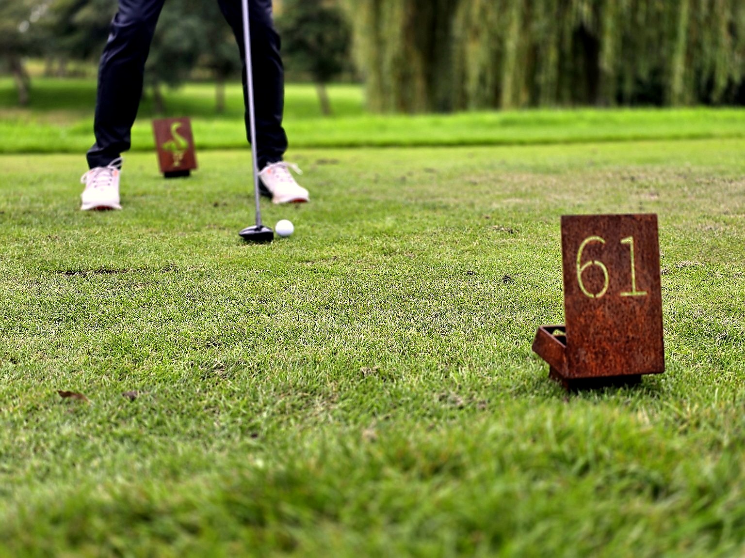 Cortenstalen teebordjes met uitgesneden nummer en gans op de afslagplaats van De Goese Golf